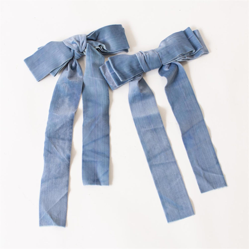 Two dusty blue velvet ribbon bows with long tails on a white background, ideal for hair accessories or gift wrapping.