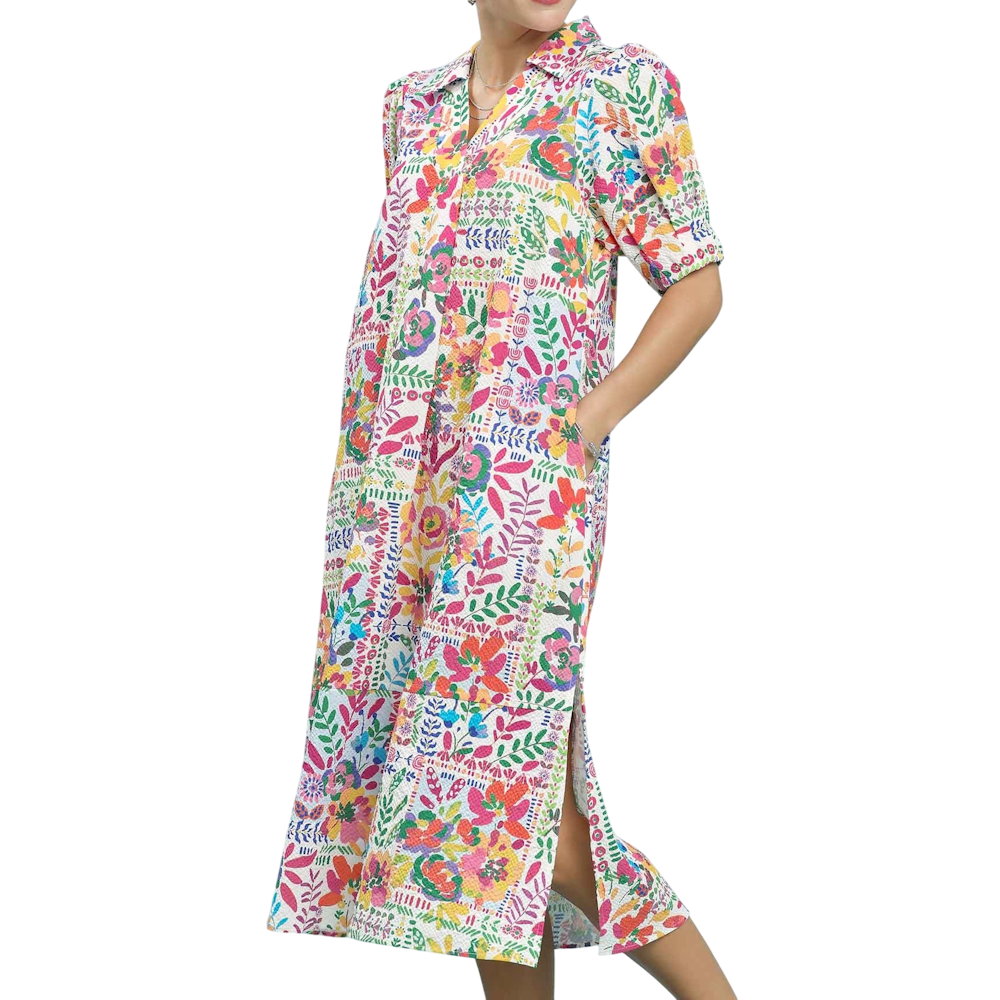 A person wearing a vibrant, multicolored floral patchwork midi dress with short sleeves and a side slit.