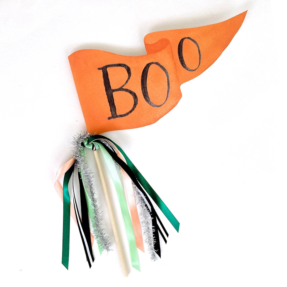 Orange Halloween pennant flag with black "BOO" lettering and decorative ribbons on a wooden stick.