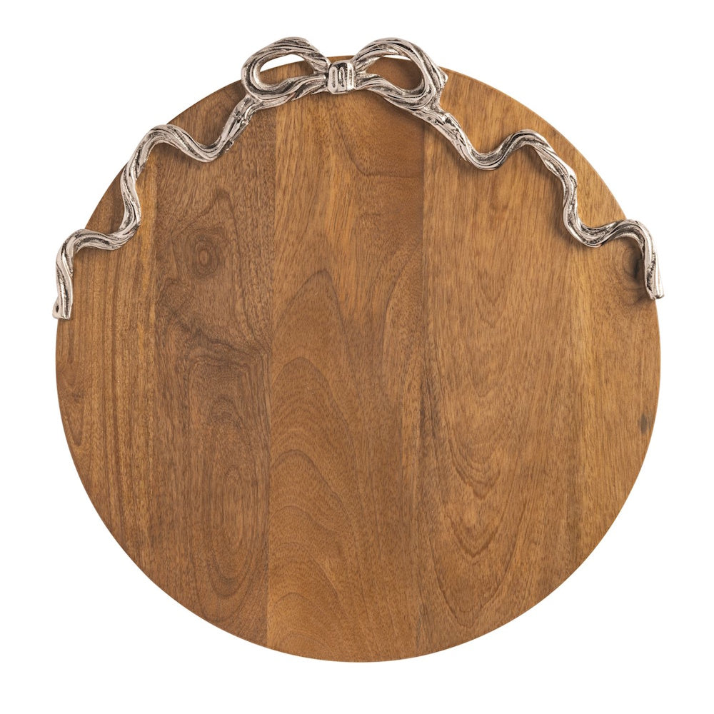 Round wooden serving board with a decorative silver ribbon and bow accent along the top edge, isolated on white.