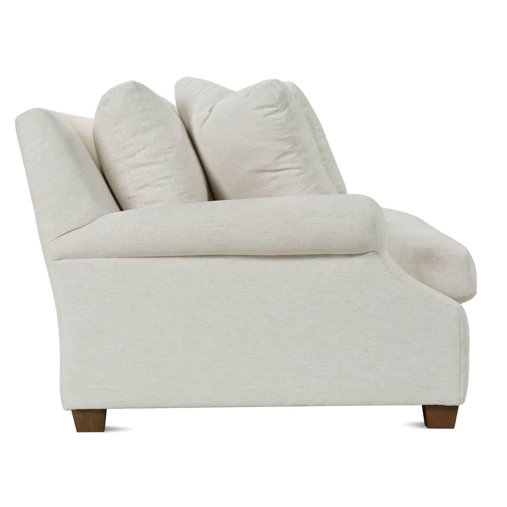 Side profile of a modern cream fabric sofa with rolled arms and wooden legs.