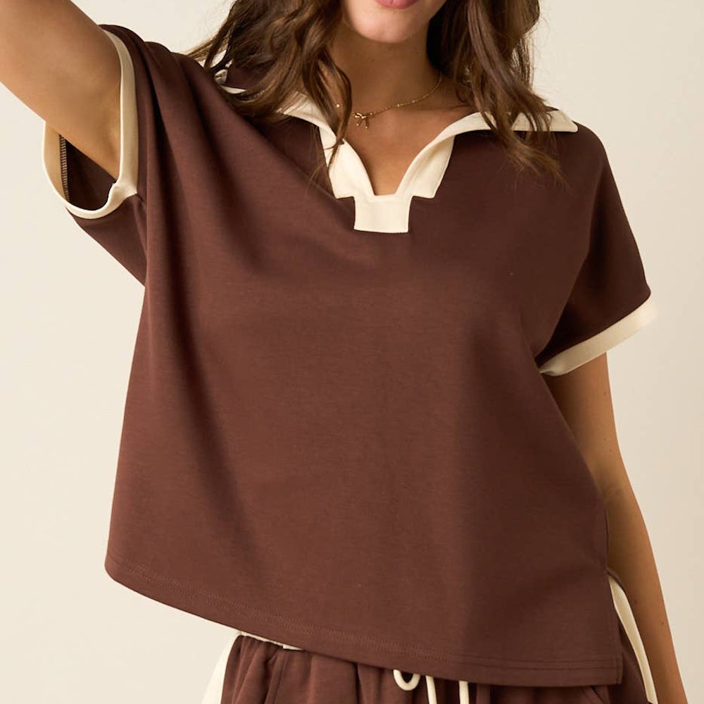 Brown short-sleeve polo top with cream trim along the split neckline and sleeve cuffs.