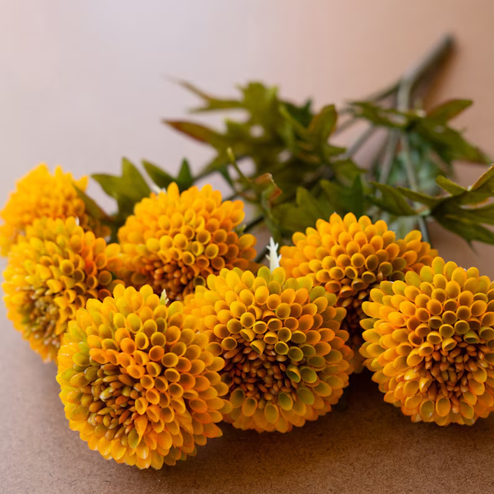 Close-up view of a bundle of artificial mustard yellow ball dahlias showing rounded flower heads.
