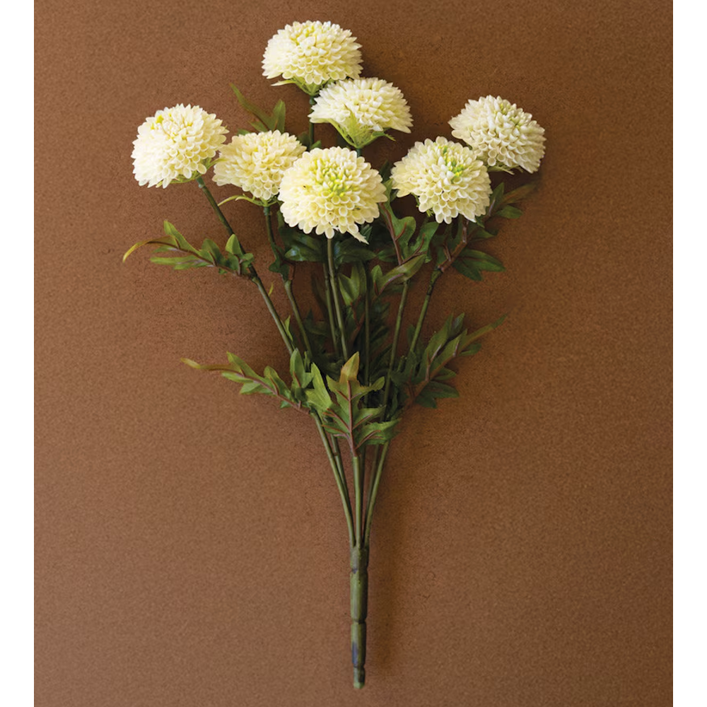 Bundle of artificial cream white ball dahlias with green stems on a brown backdrop.
