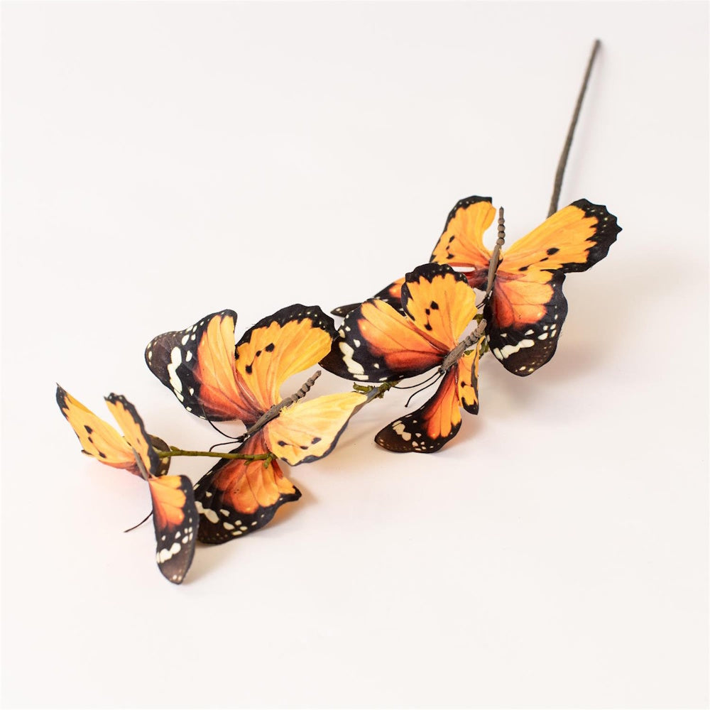 Artificial stem with decorative orange monarch butterflies on a plain white background.