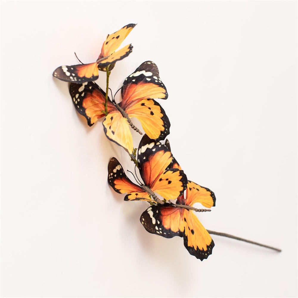 Decorative stem lined with artificial orange and black monarch butterflies on a white background.