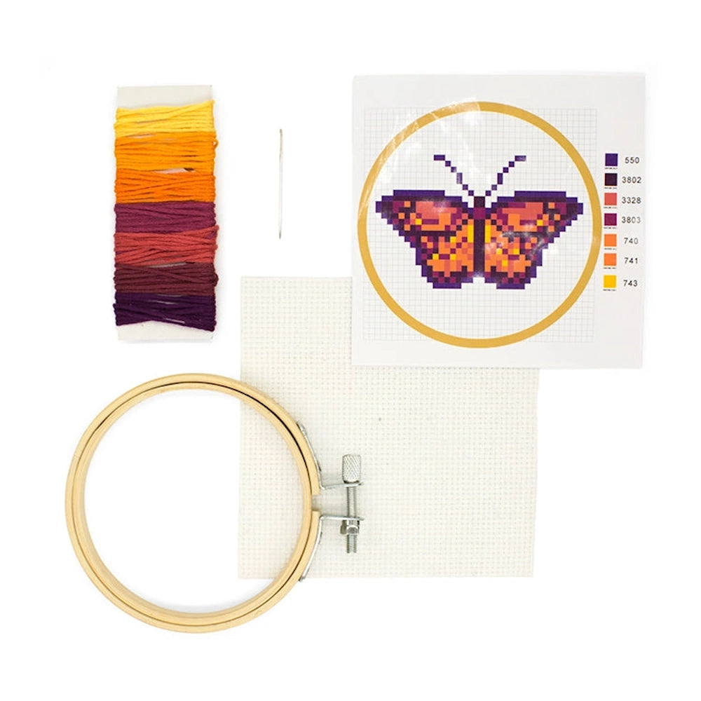 Butterfly mini cross-stitch kit with colorful embroidery floss, needle, fabric, hoop, and pixelated butterfly pattern.