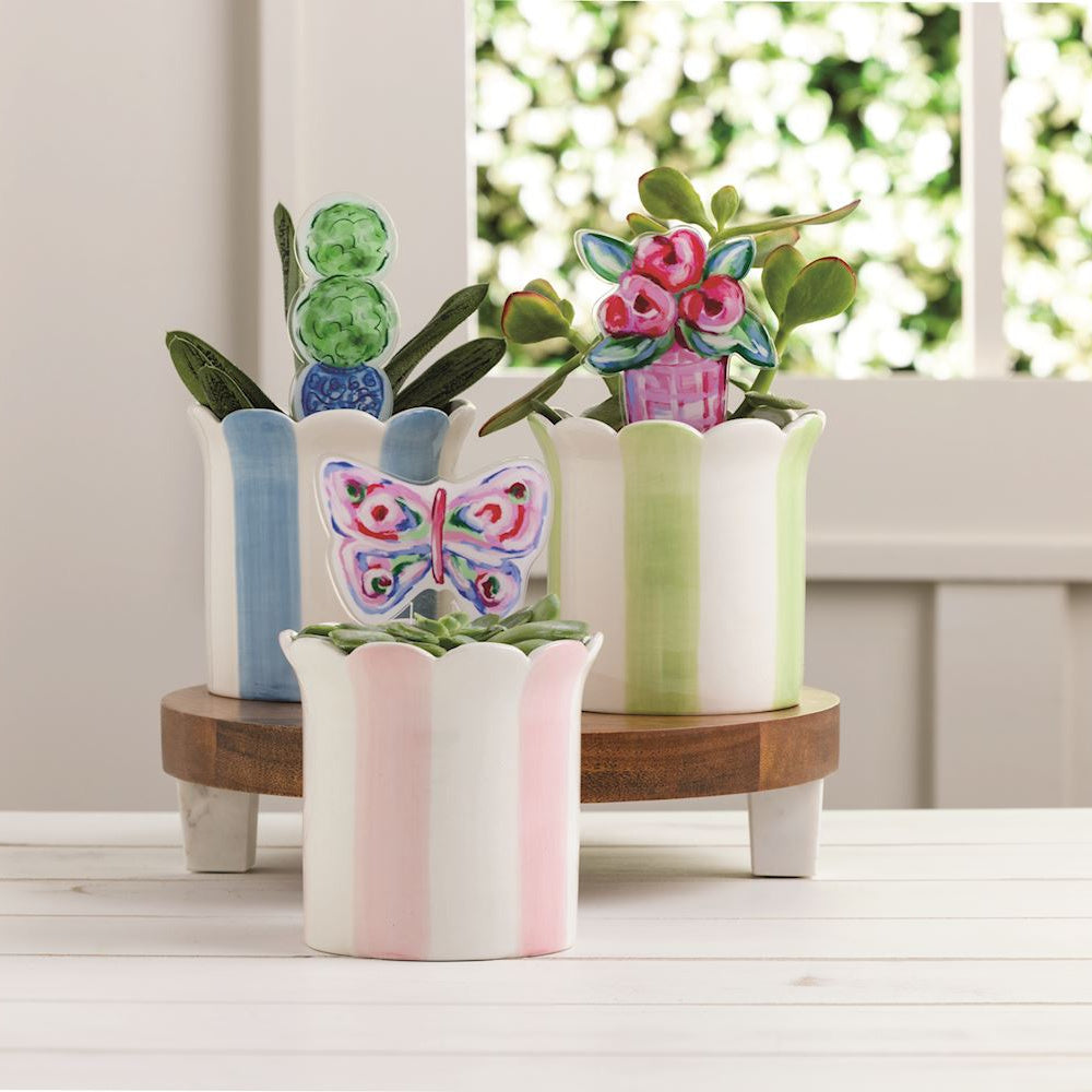 Hand-painted striped ceramic succulent pots with decorative butterfly, flower, and topiary plant stakes on a wooden stand.