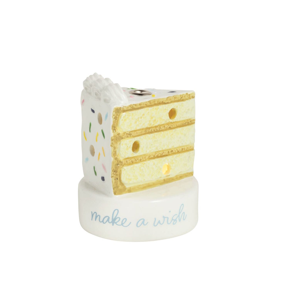 Ceramic birthday cake slice candle holder with "make a wish" text, sprinkles, and light-up base on a white background.