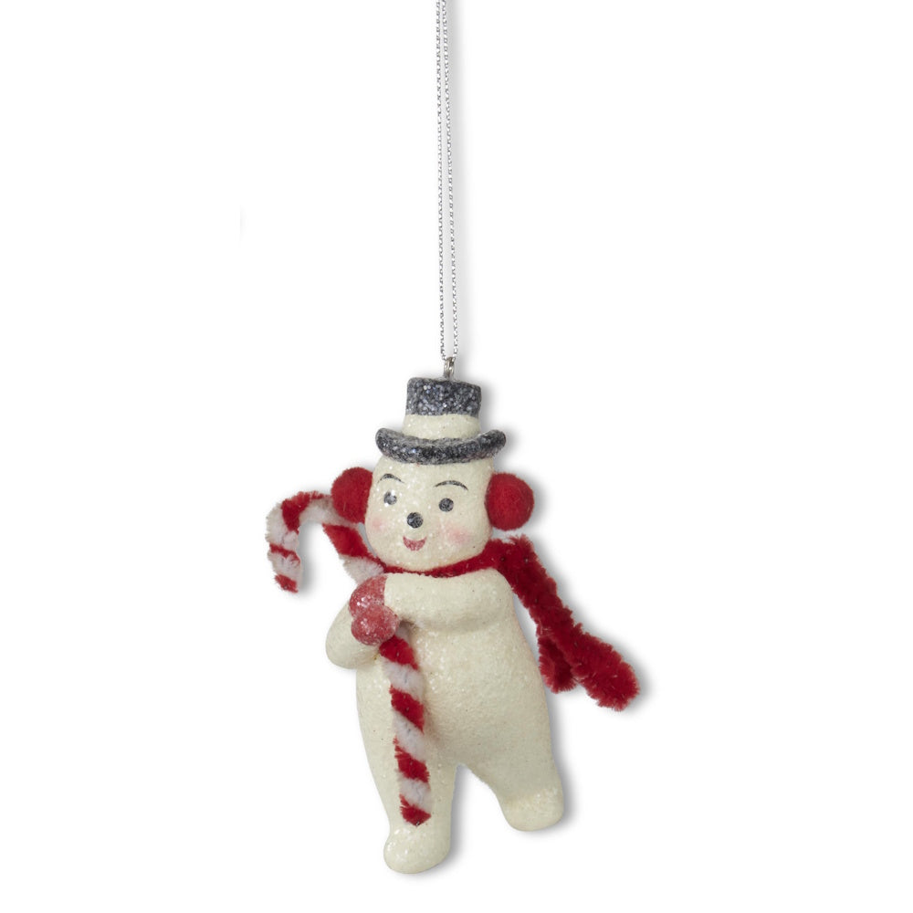 A hanging glittered snowman ornament wearing earmuffs, a scarf, and a top hat while holding a candy cane.