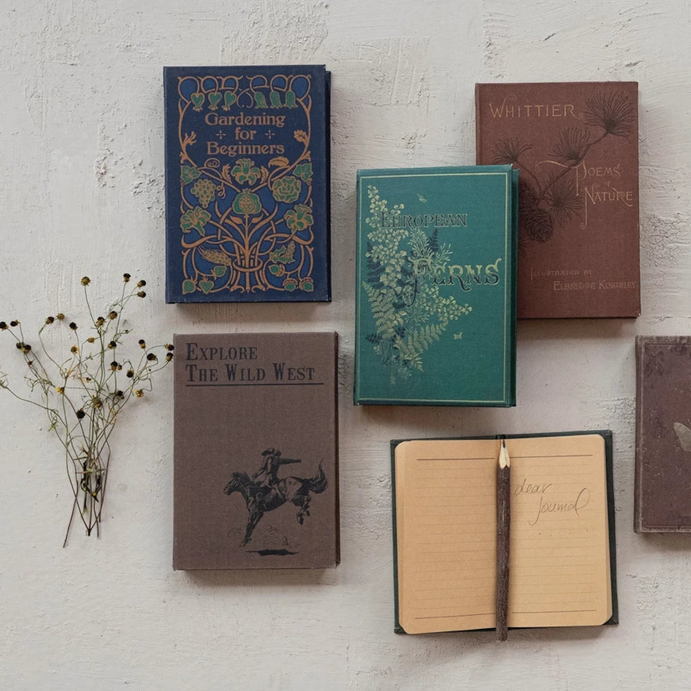 Vintage-style book-bound notebooks and a twig pencil on a textured surface, perfect for nature journaling and stationery.