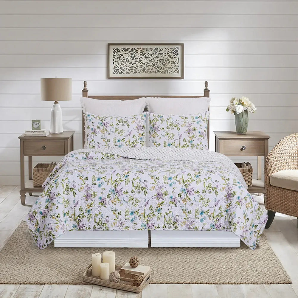 A cozy bedroom featuring a floral quilt and matching shams on a wooden bed, flanked by two side tables.