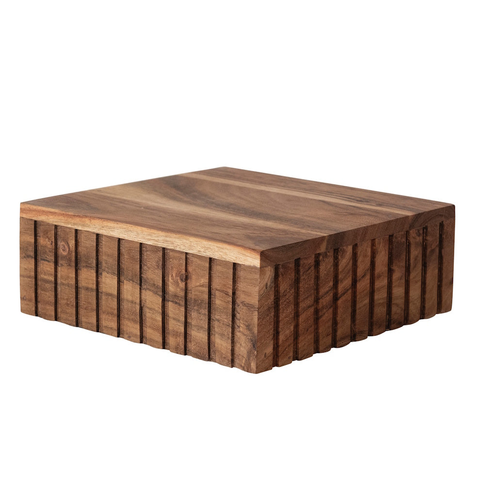 Square mango wood platform serving board with carved vertical ridges on its sides on a white background.