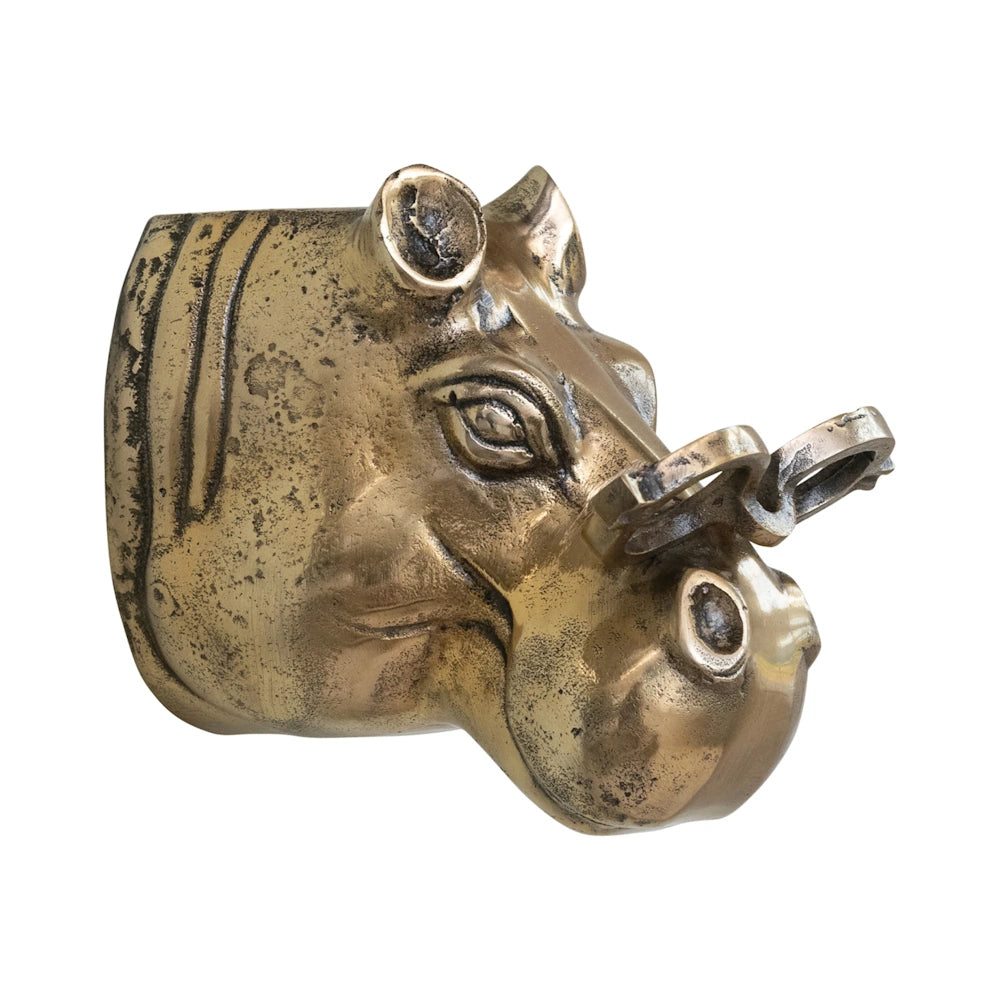 Side profile view of a metallic brass hippo head wall mount wearing round eyeglasses on a plain white background.