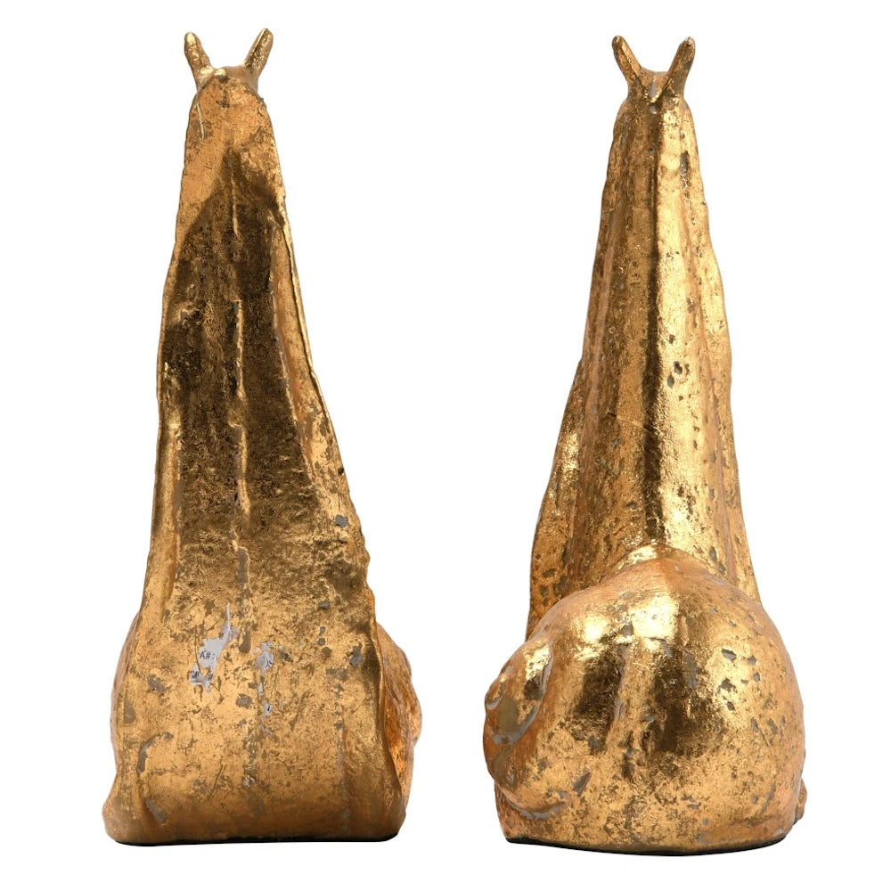 Decorative brass snail sculptures for home office shelf decor and book organization.
