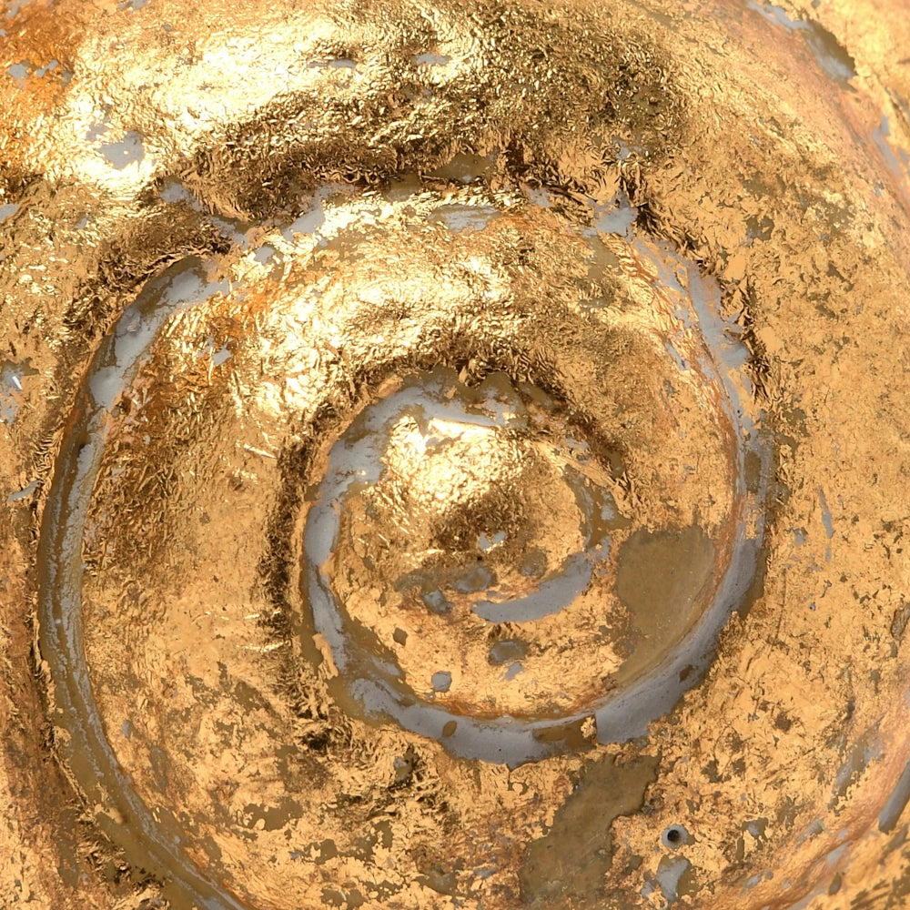 Detailed close-up of a spiral-shaped object covered in textured, weathered gold leaf with a metallic, aged finish.
