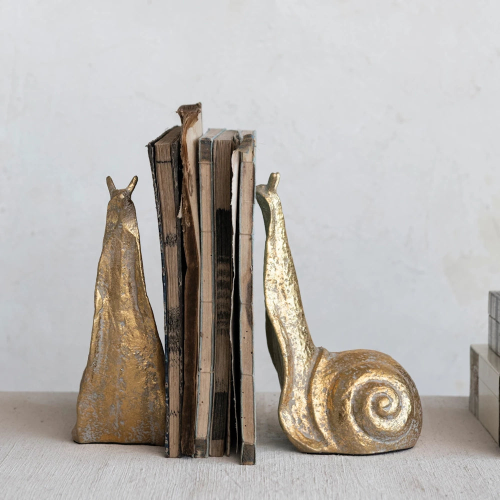 Decorative gold snail bookends with antique books for home office shelf decor.