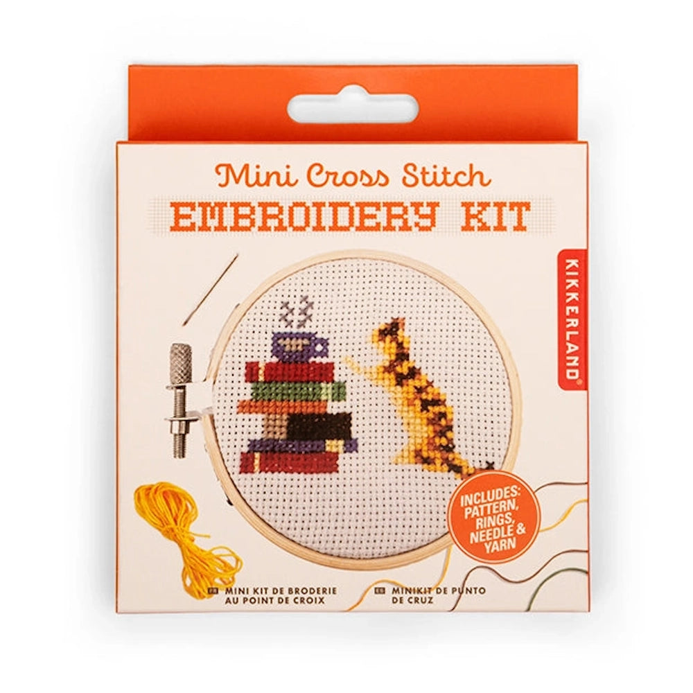 Kikkerland Mini Cross Stitch Embroidery Kit featuring a ginger cat next to a stack of books and a coffee cup.