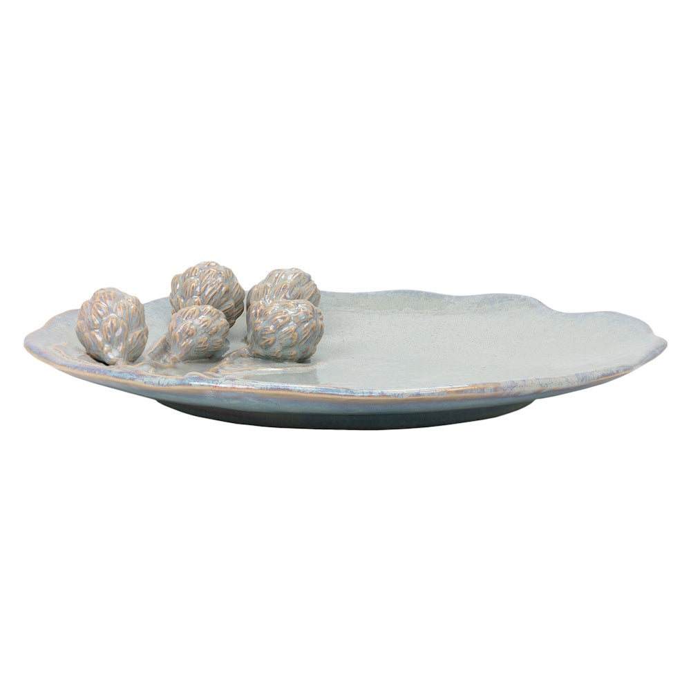 Pale blue ceramic serving platter featuring 3D artichoke accents and an irregular, scalloped edge on a white background.