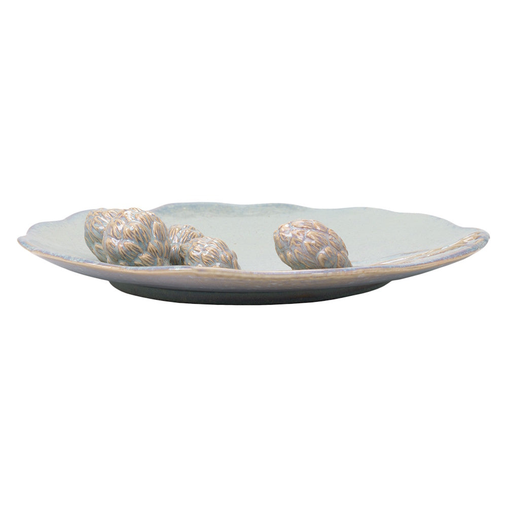Side profile of a light blue ceramic artichoke platter with textured details and a scalloped edge on white.