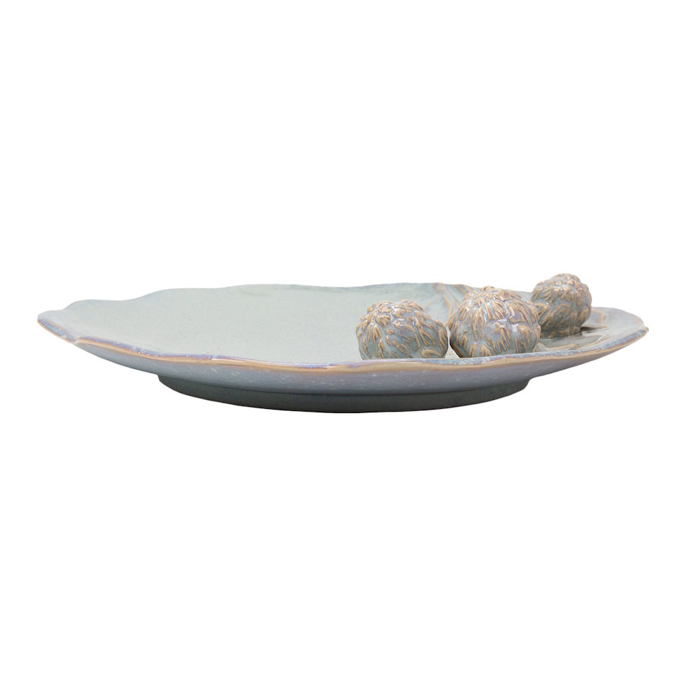 Side view of a pale blue Cazaria ceramic platter featuring raised, textured artichoke motifs and an organic rim.