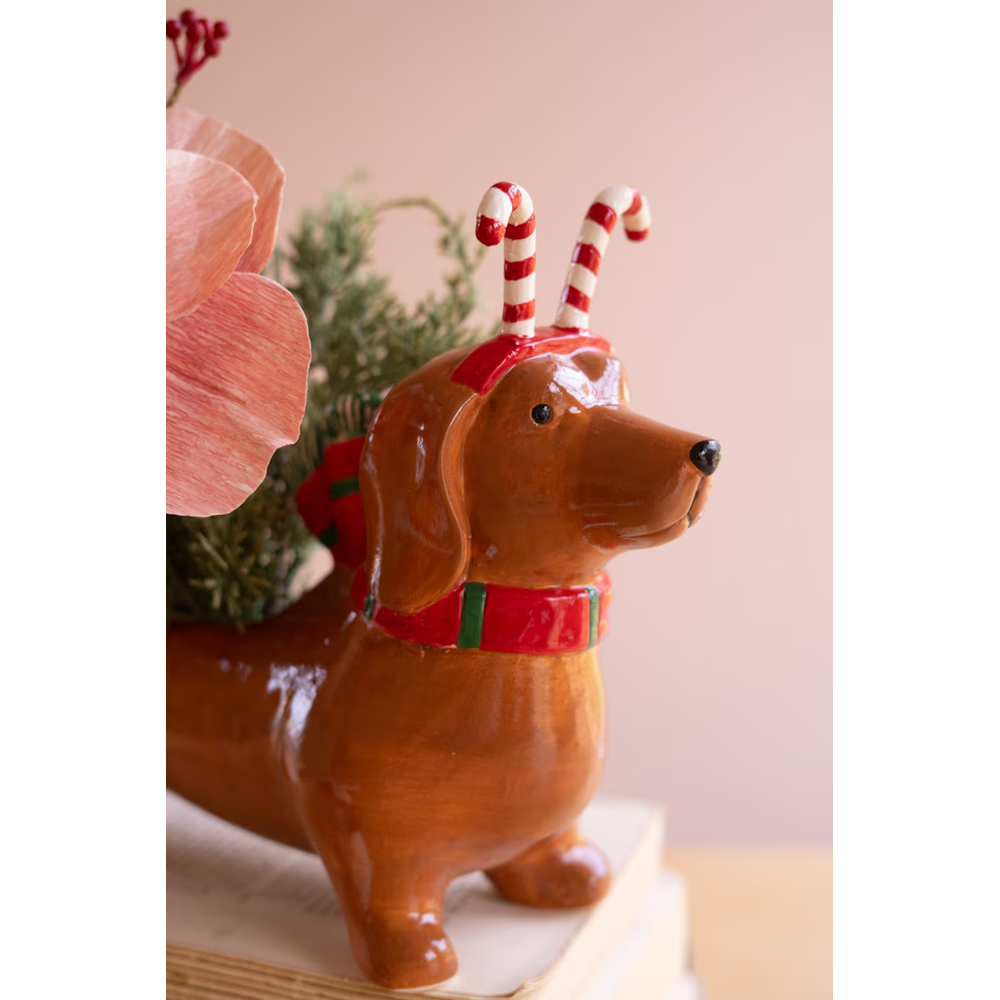 Detailed view of ceramic dachshund planter wearing candy cane headband and holiday scarf.