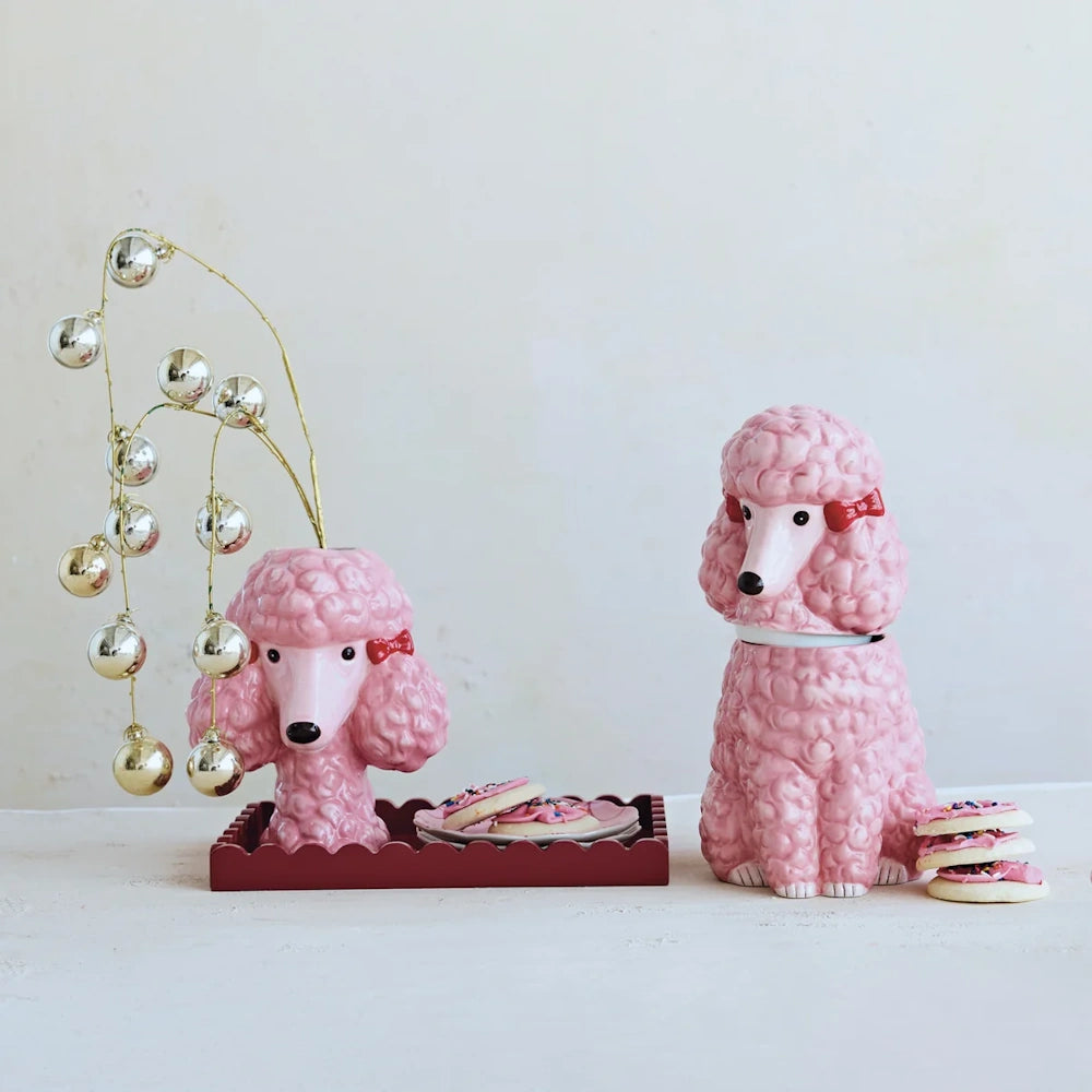 Pink ceramic poodle cookie jar displayed next to a matching poodle vase with gold ornaments and frosted cookies.