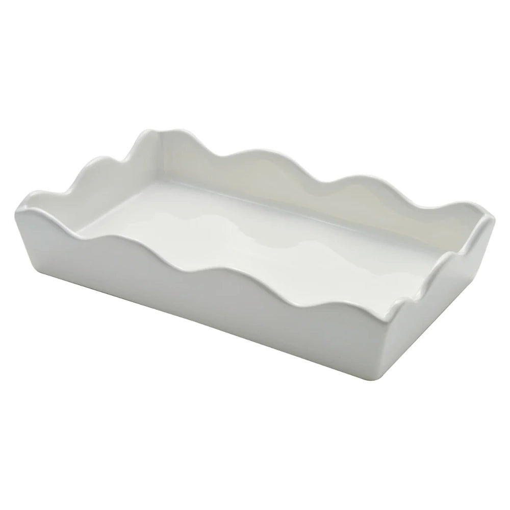Side angle view of a white ceramic guest towel tray with a wavy rim style.