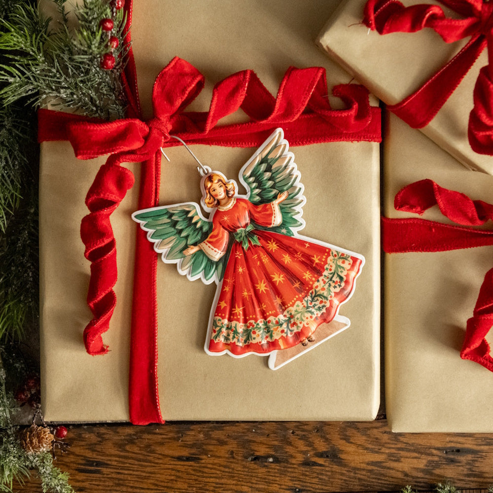 Vintage-style Christmas angel ornament attached to a gift wrapped in kraft paper with red velvet ribbon.