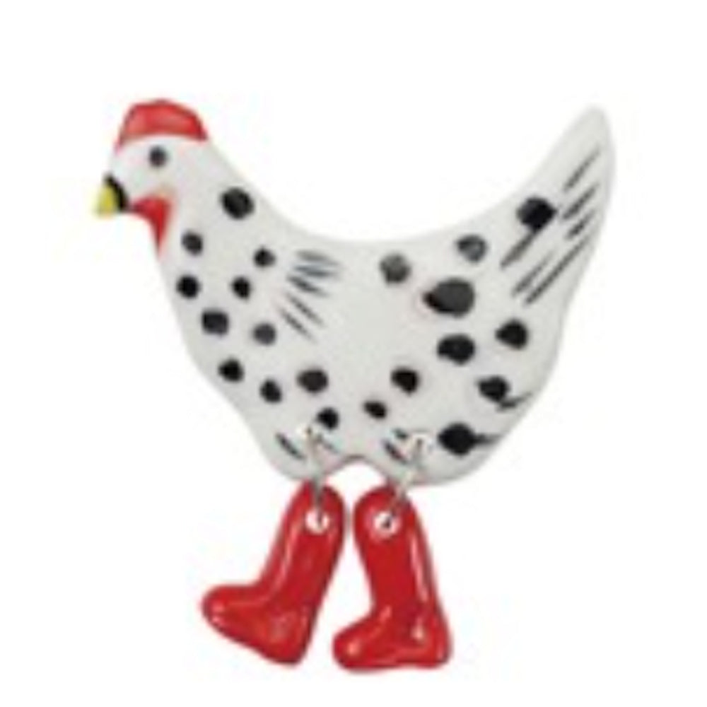 A ceramic white chicken magnet with black spots and dangling legs wearing bright red rain boots.