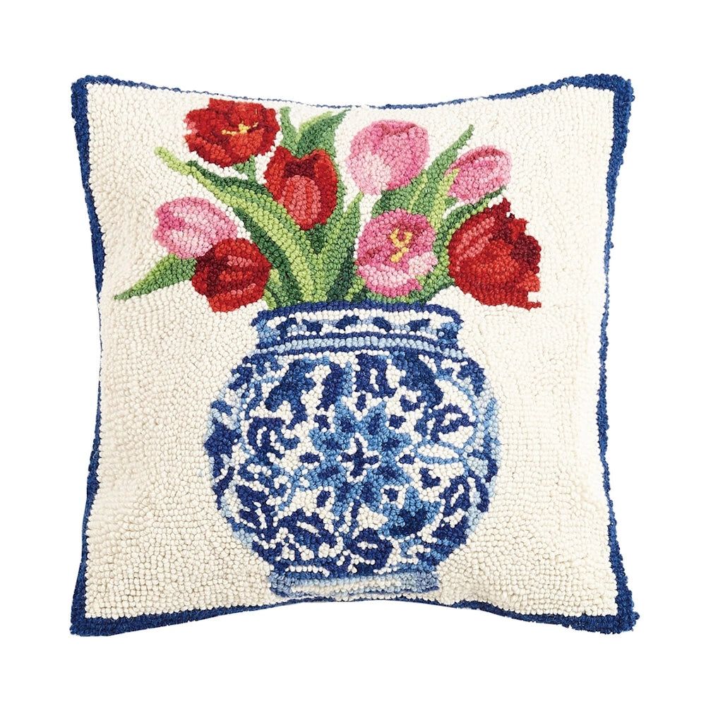 Chinoiserie blue and white ginger jar vase with red and pink tulips on a white hooked wool decorative throw pillow.