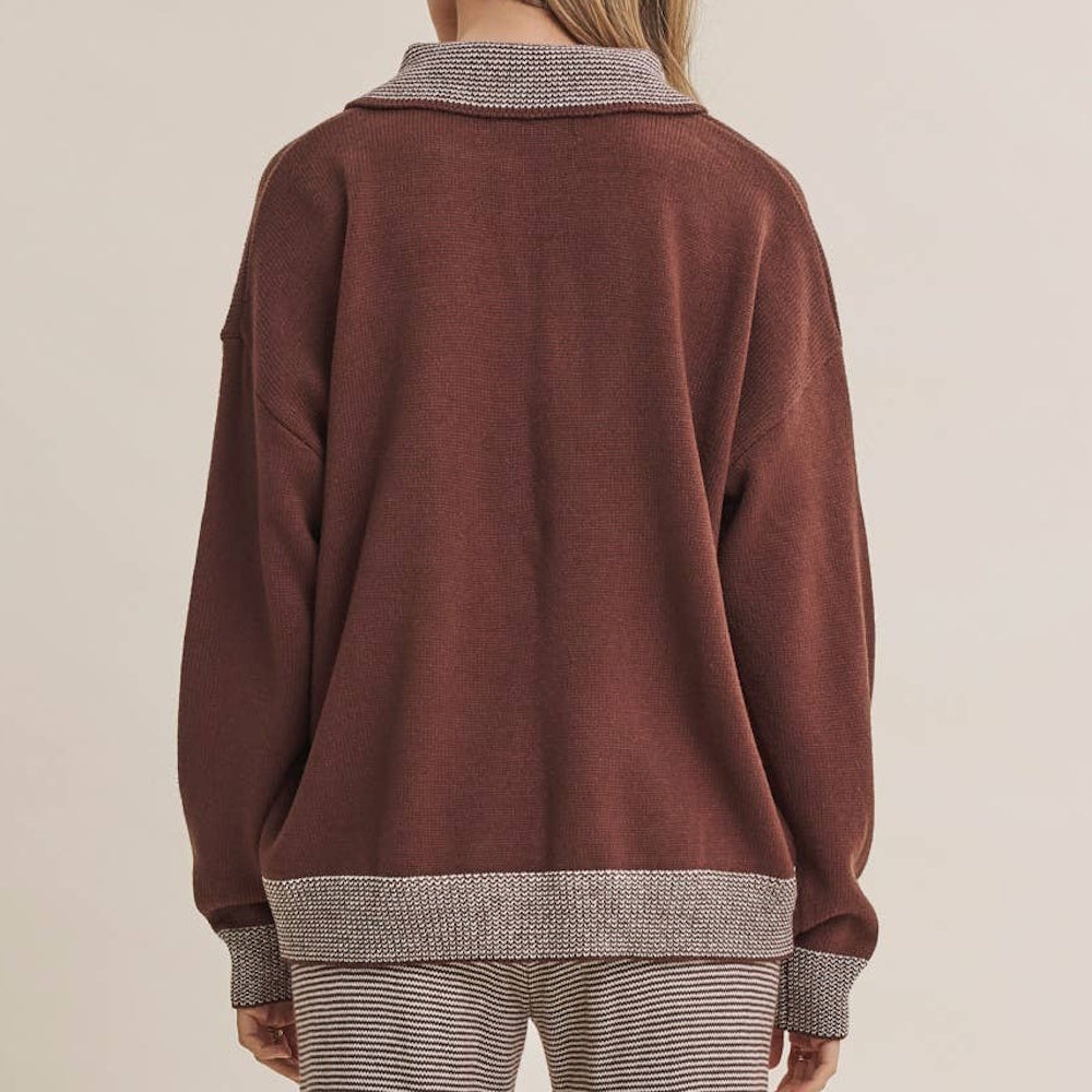 Back view of a relaxed brown knit sweater with pattern trim on the collar, hem, and long sleeve cuffs.