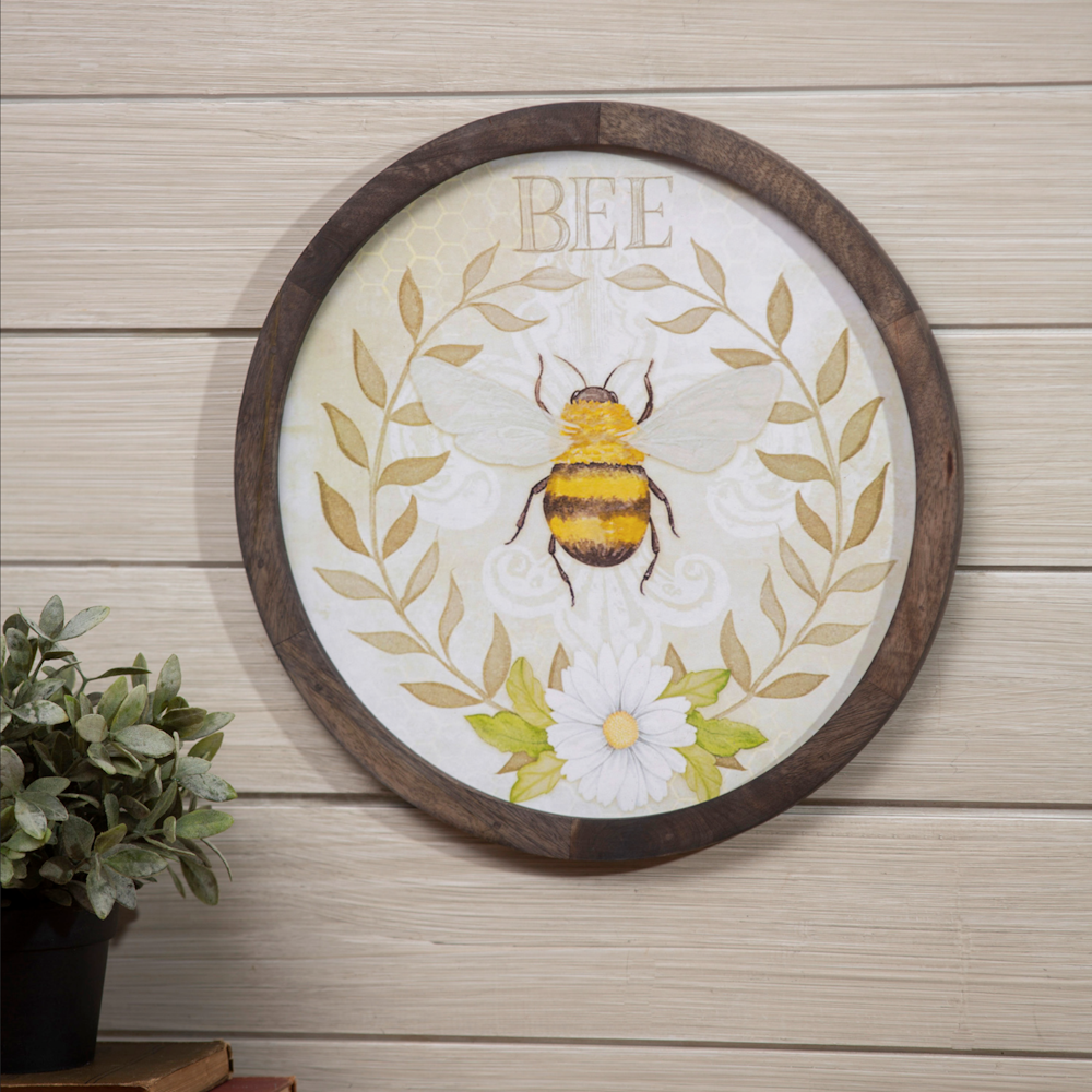 Round wooden wall art featuring a bumblebee illustration, a daisy, and the word "BEE" inside a leafy wreath.