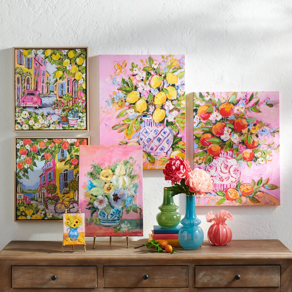 A colorful gallery wall of floral and citrus-themed impressionist paintings displayed above a wooden dresser.