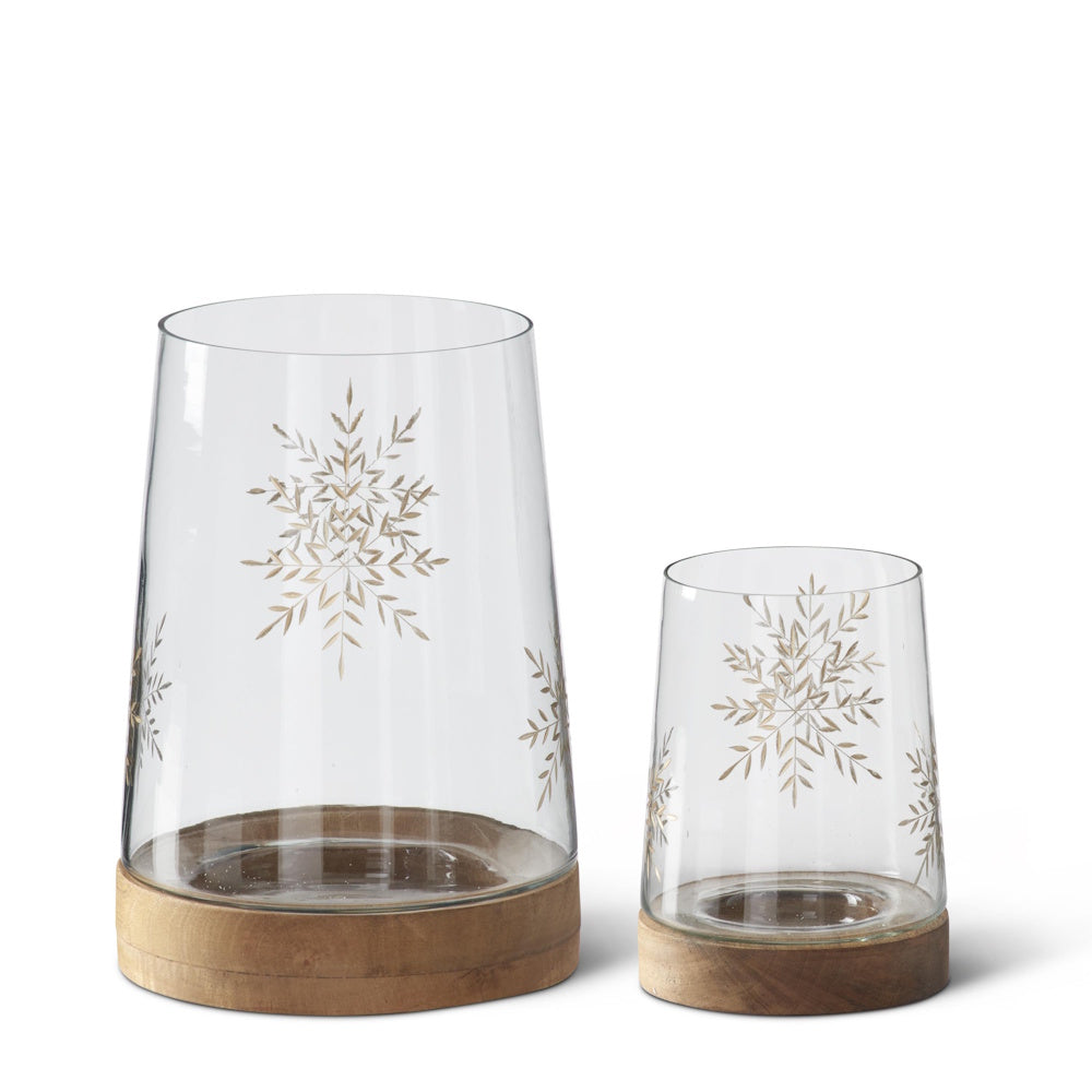 Clear glass containers with gold-etched snowflake designs and wooden bases.