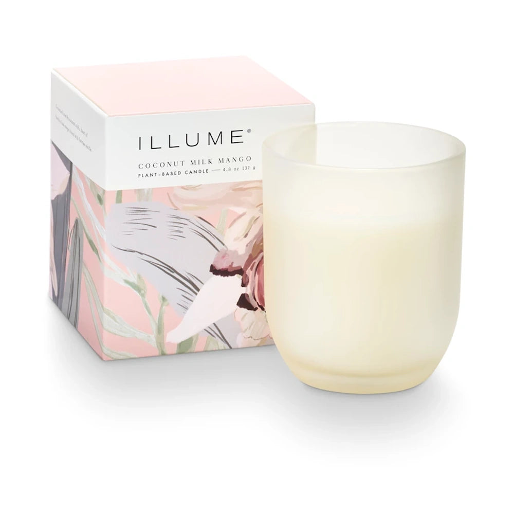 Illume Coconut Milk Mango plant-based candle in a frosted glass jar next to its pink floral decorative box.