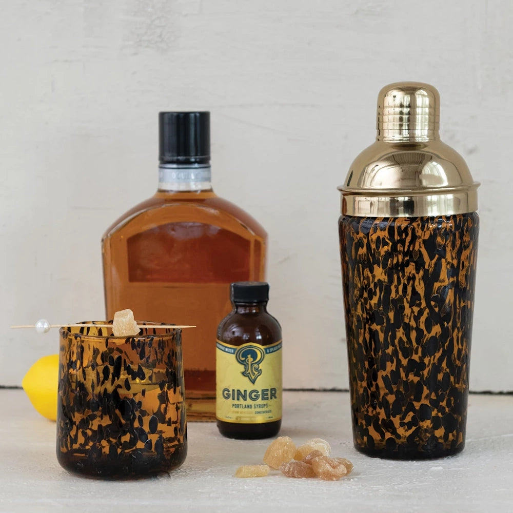 Confetti glass cocktail shaker and matching tumbler with tortoiseshell pattern, gold top, and ginger cocktail ingredients.