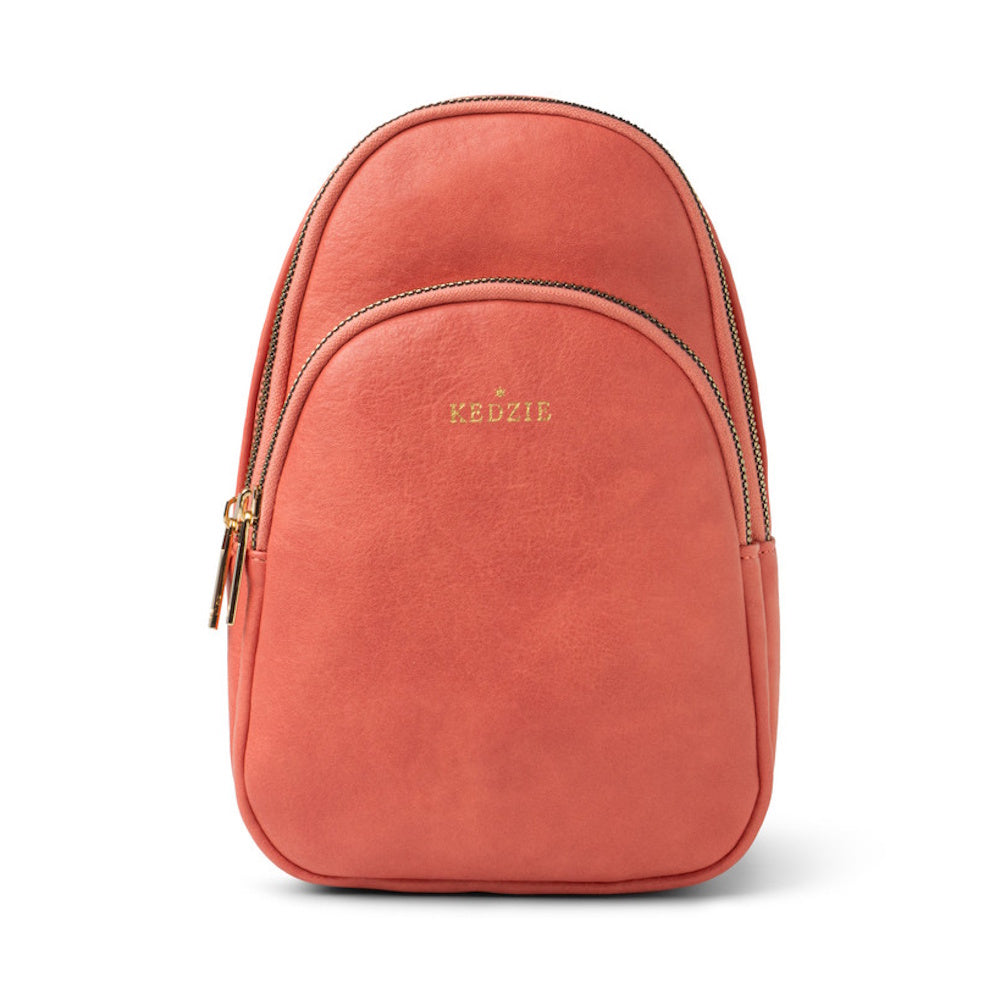 Coral pink Kedzie mini backpack sling bag with gold zippers isolated on a white background.