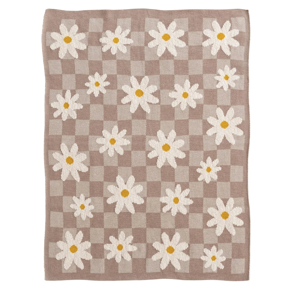 Knitted baby blanket with a tan and white checkered pattern and scattered white daisy flowers with yellow centers.