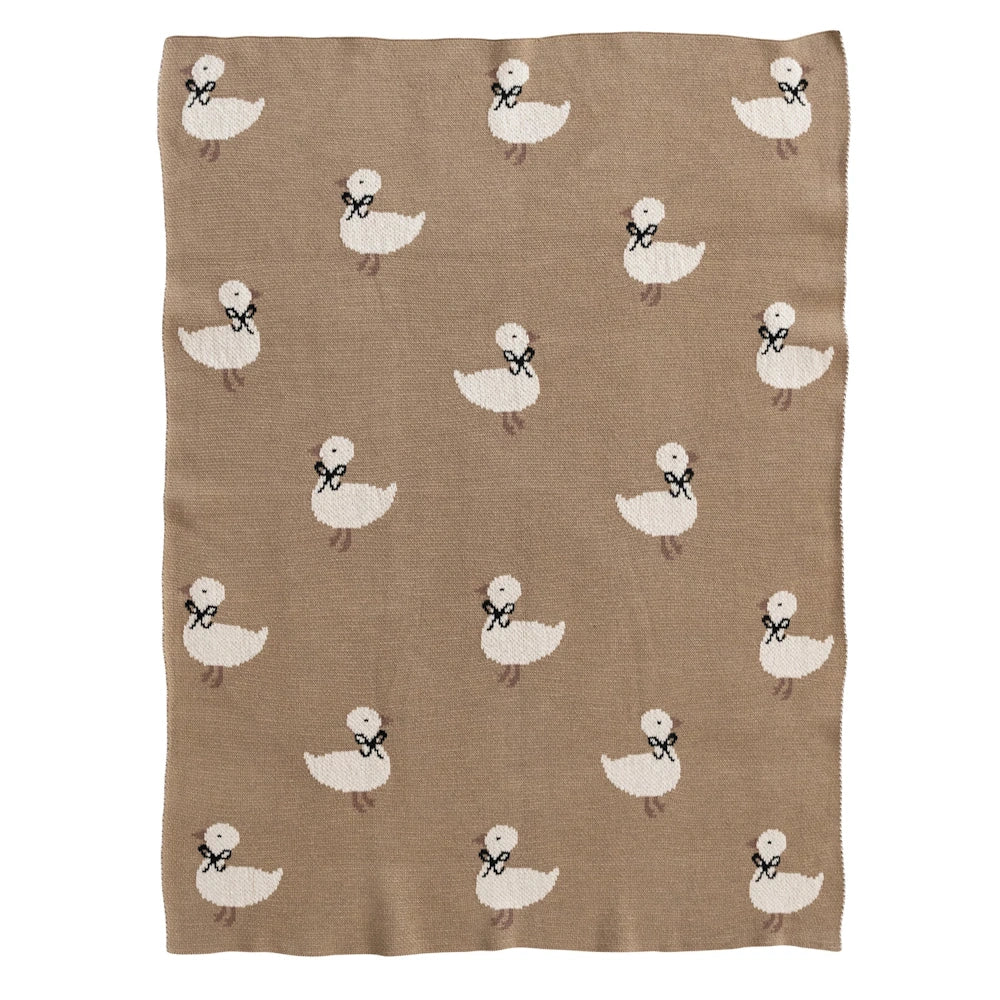Brown cotton knit baby blanket featuring a repeating white duckling pattern with black bows.