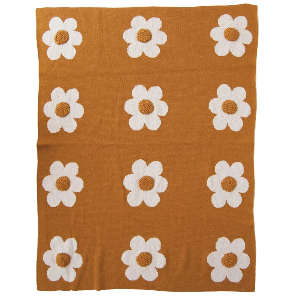 Mustard yellow knit throw blanket with white daisy flower pattern and textured centers.
