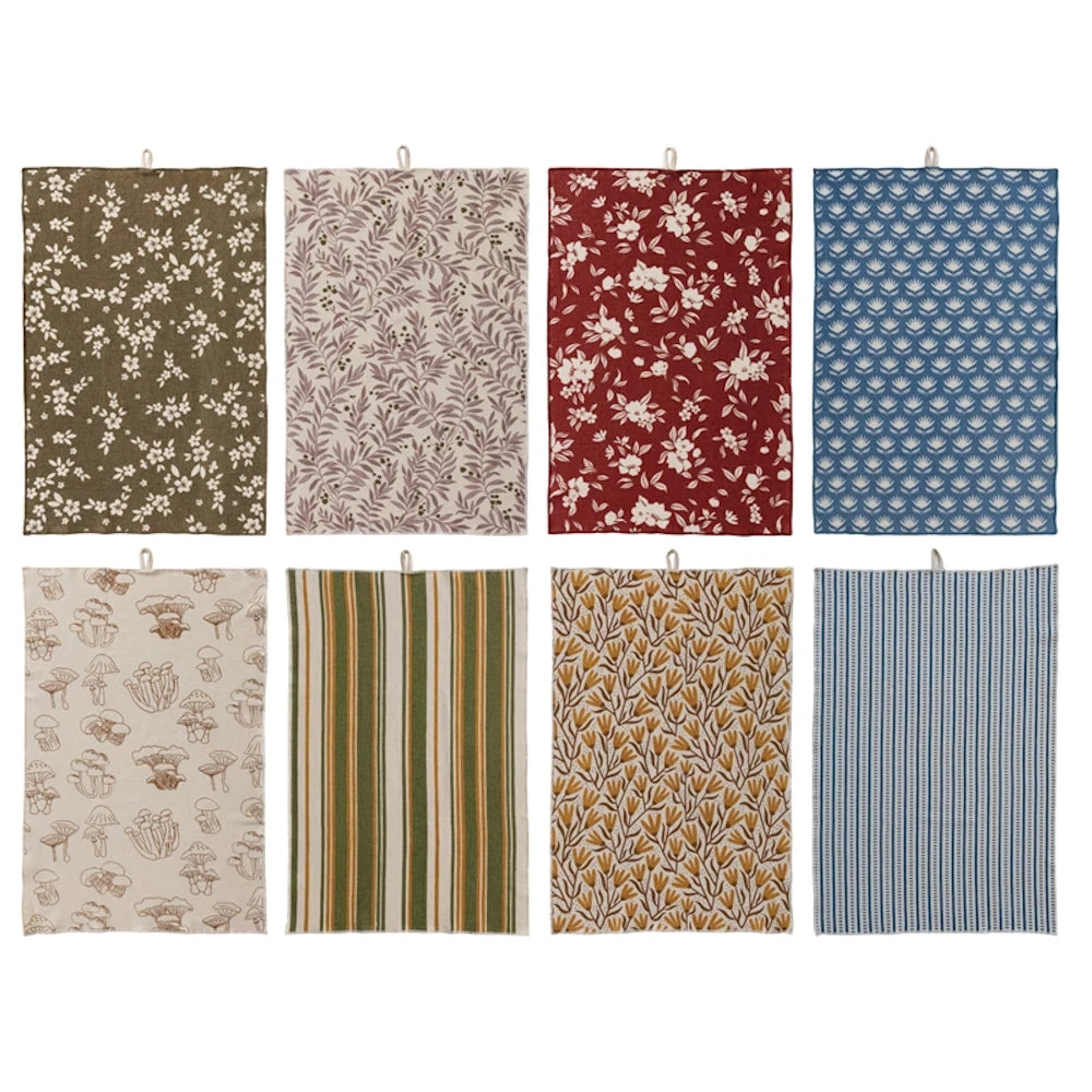 A set of eight patterned cotton tea towels in earth tones featuring floral, mushroom, and striped botanical designs.