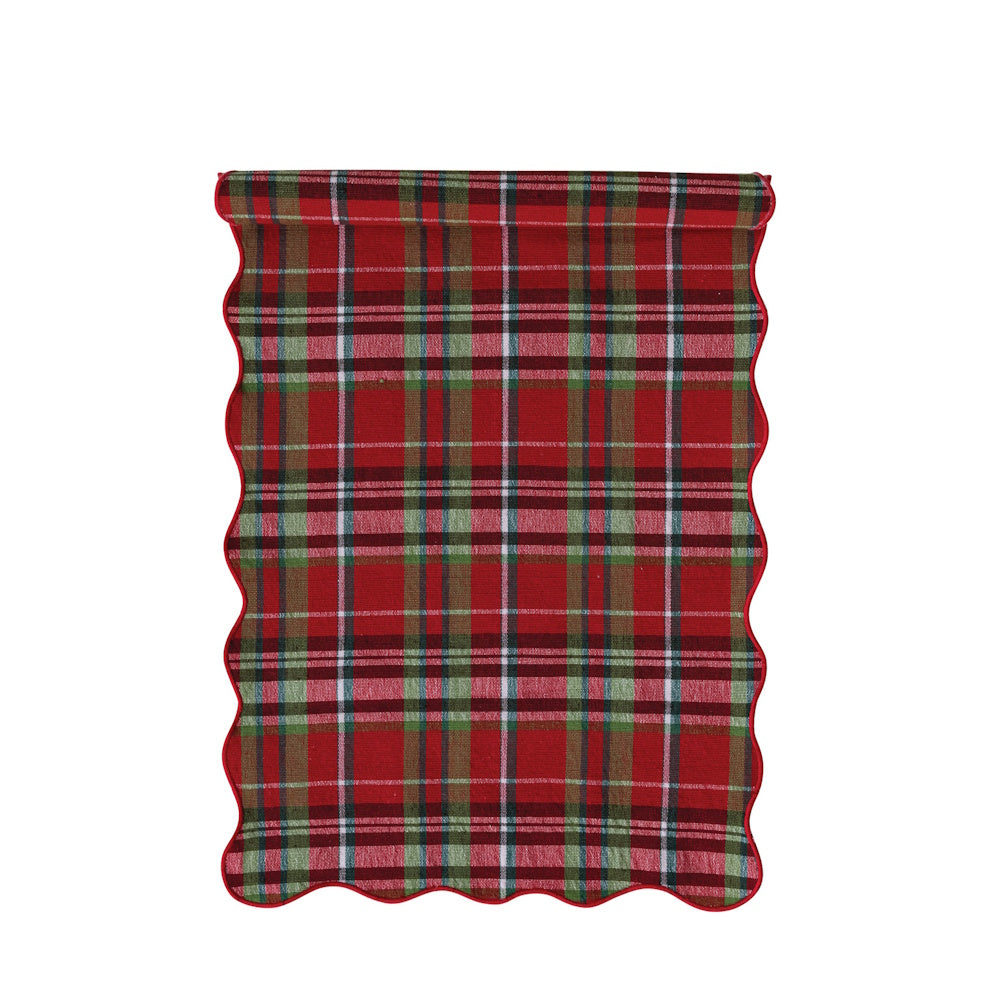 Top view of the cotton table runner featuring a red, green, and white tartan plaid pattern and a scalloped edge.