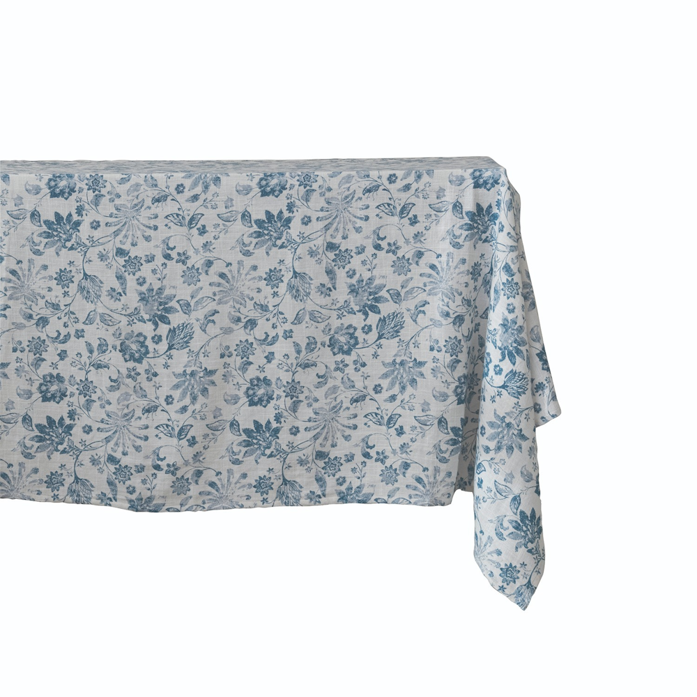 White textured tablecloth draped over a table, featuring a blue floral and botanical pattern.