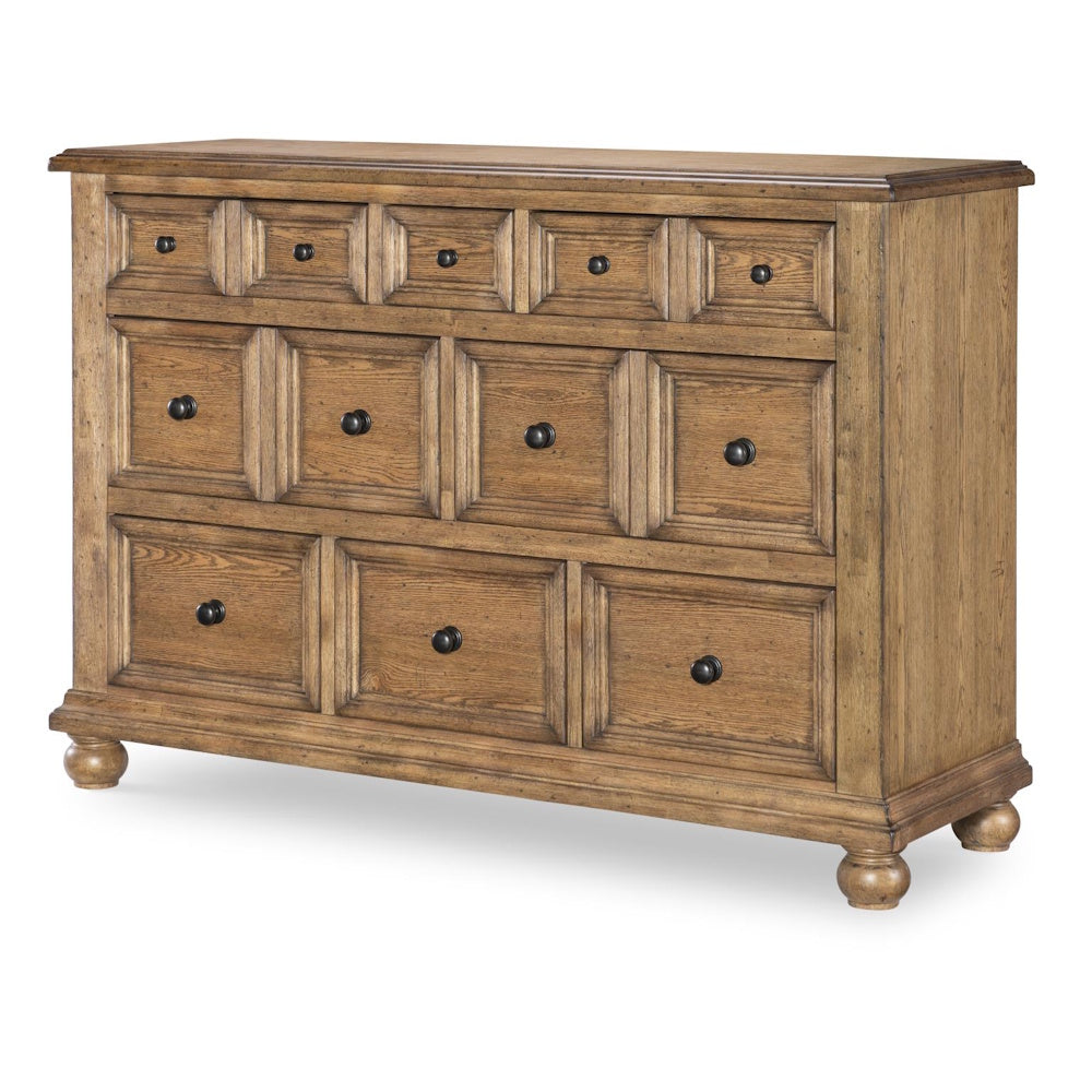 Rustic light wood dresser with eight paneled drawers and dark round knobs.