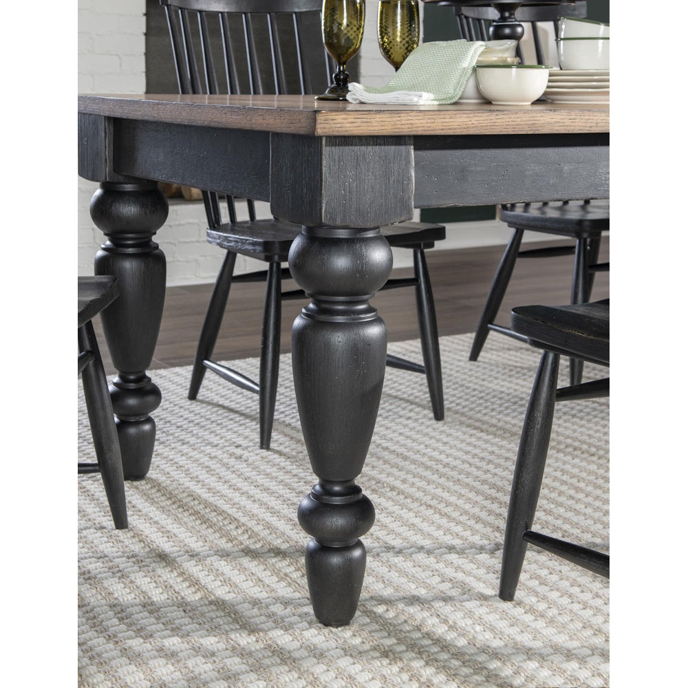 Close-up of black turned chimney-style table leg beneath a wood top dining table with matching chairs.
