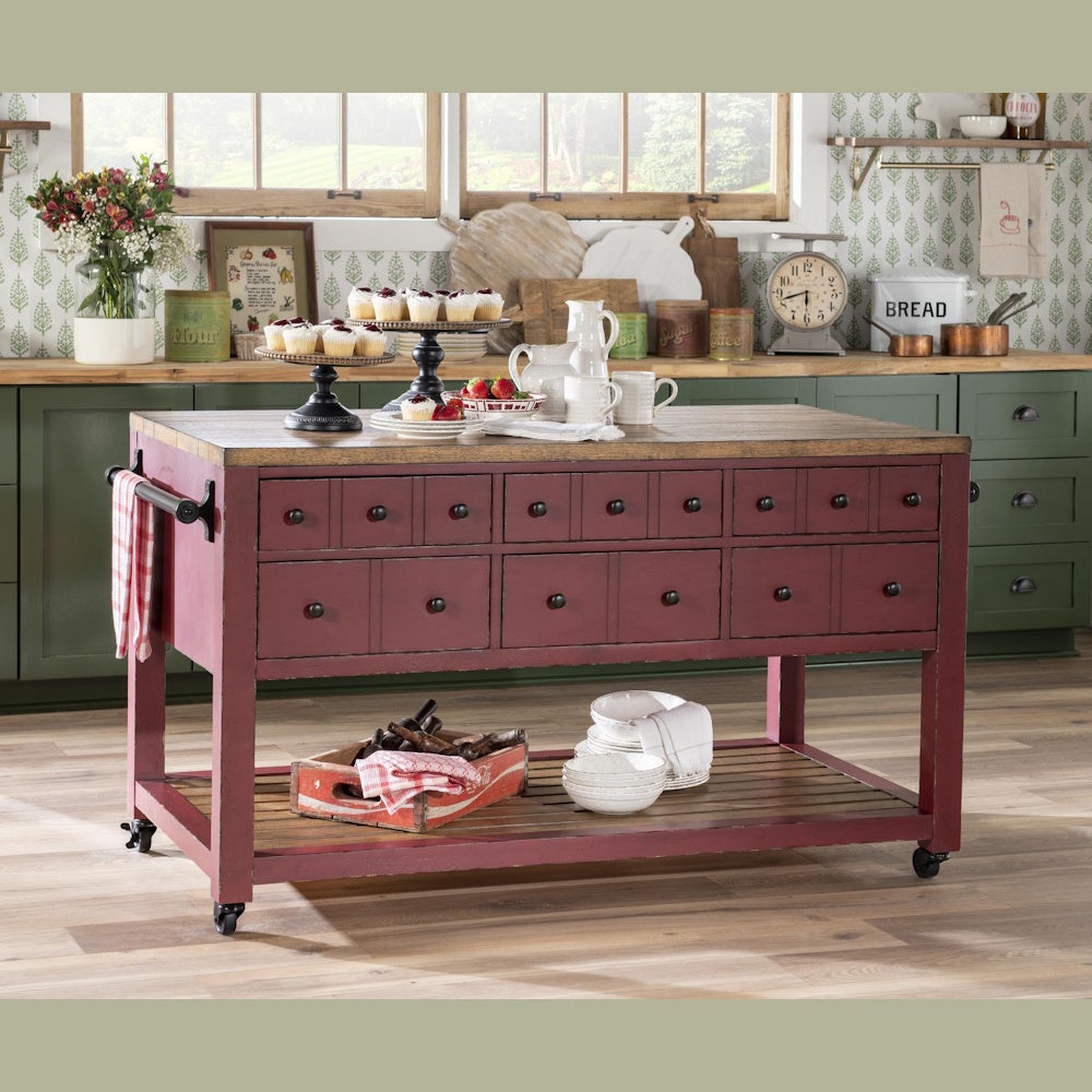 Red distressed wood kitchen island with drawers, butcher block top, and wheels in a farmhouse kitchen.