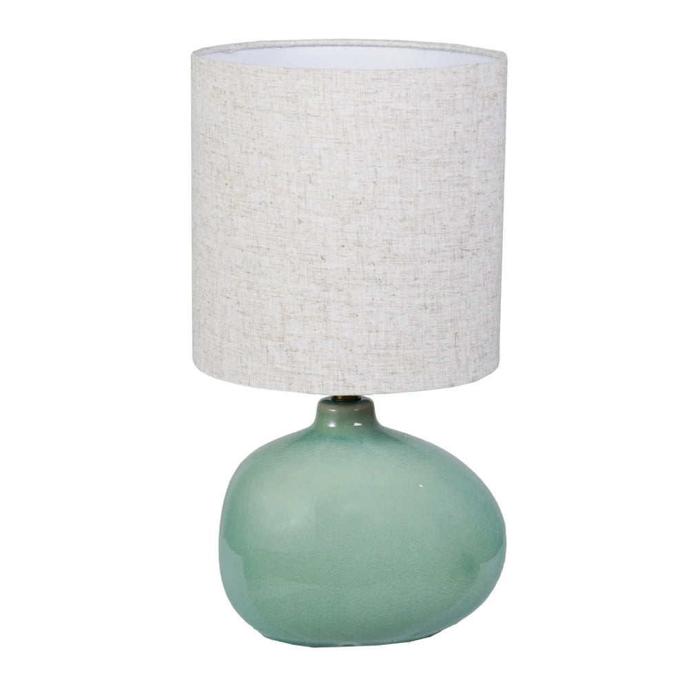 Ceramic table lamp with a sage green crackle glaze, pebble-shaped base, and a neutral textured linen drum shade.