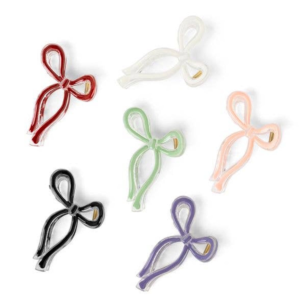 Six colorful bow-shaped hair clips in red, white, pink, green, black, and purple on a white background.