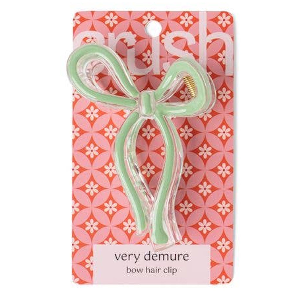 Mint green bow hair clip on pink floral packaging, titled "very demure." Simple, stylish hair accessory for women.